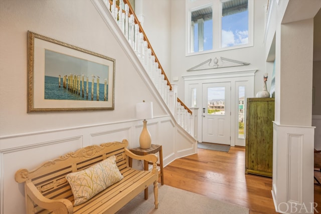 entrance foyer with a decorative wall, stairway, plenty of natural light, and light wood-style floors