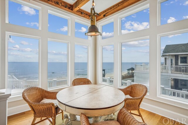 sunroom featuring beam ceiling and a water view