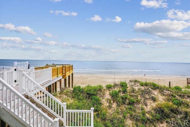 property view of water featuring stairway and a beach view