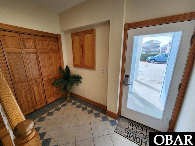 doorway to outside featuring light tile patterned floors and baseboards