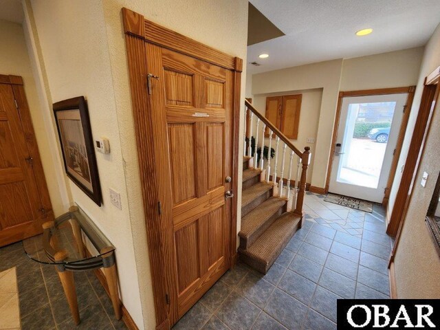 foyer entrance with recessed lighting, dark tile patterned flooring, baseboards, and stairs