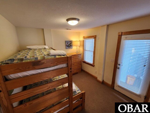 bedroom featuring a textured ceiling, carpet flooring, visible vents, and baseboards