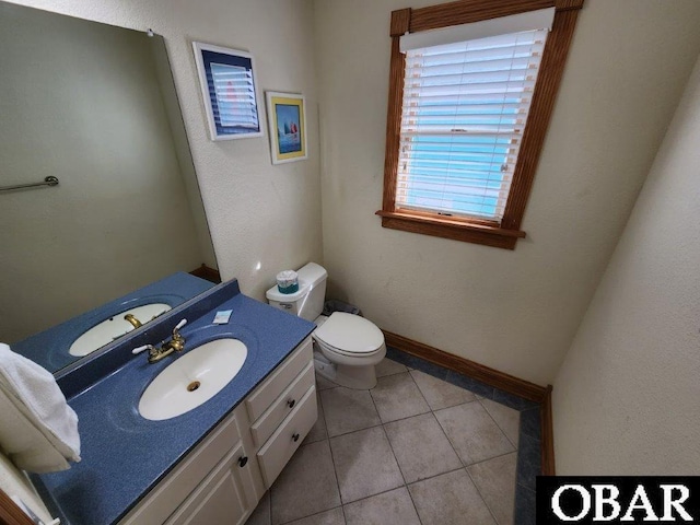 bathroom with toilet, tile patterned flooring, baseboards, and vanity