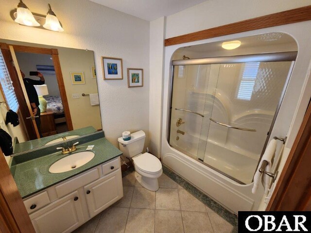 bathroom with ensuite bathroom, toilet, vanity, combined bath / shower with glass door, and tile patterned floors