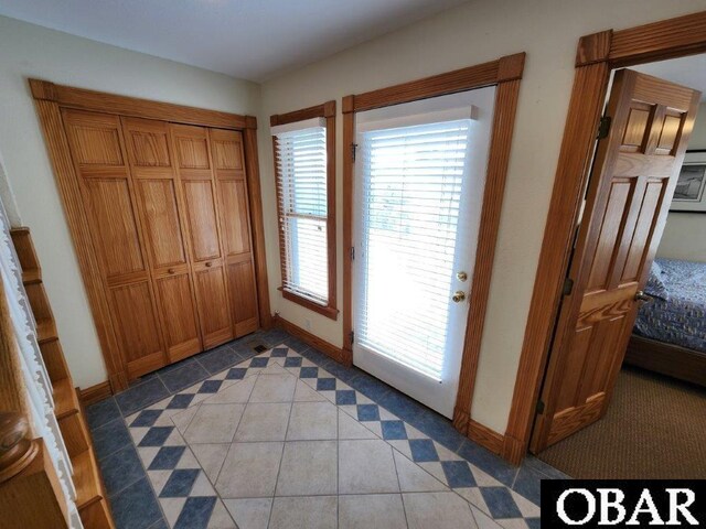 doorway featuring light tile patterned floors and baseboards