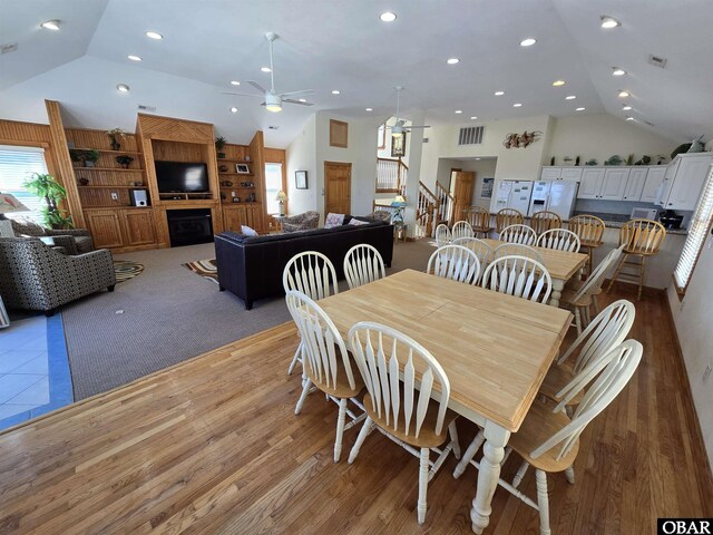 dining space featuring a fireplace, lofted ceiling, recessed lighting, visible vents, and stairs