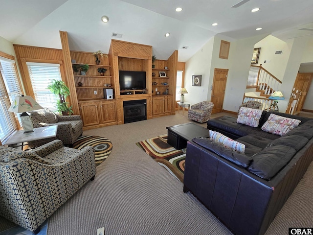 carpeted living room with high vaulted ceiling, recessed lighting, a large fireplace, visible vents, and stairway