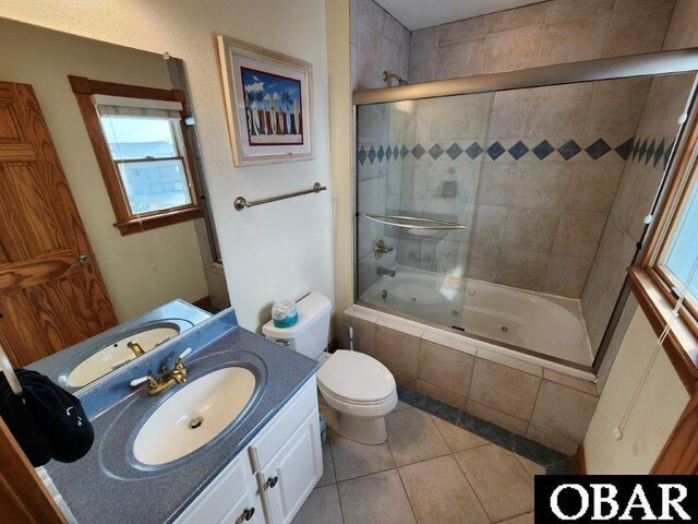 full bath with a combined bath / shower with jetted tub, tile patterned floors, toilet, and vanity