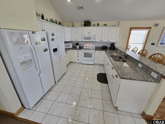 kitchen with visible vents, white cabinetry, a sink, dark stone counters, and white appliances