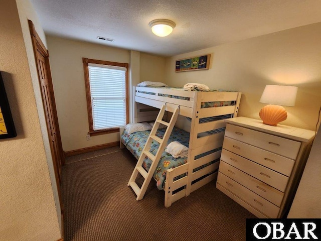 bedroom featuring baseboards, visible vents, dark carpet, and a textured ceiling