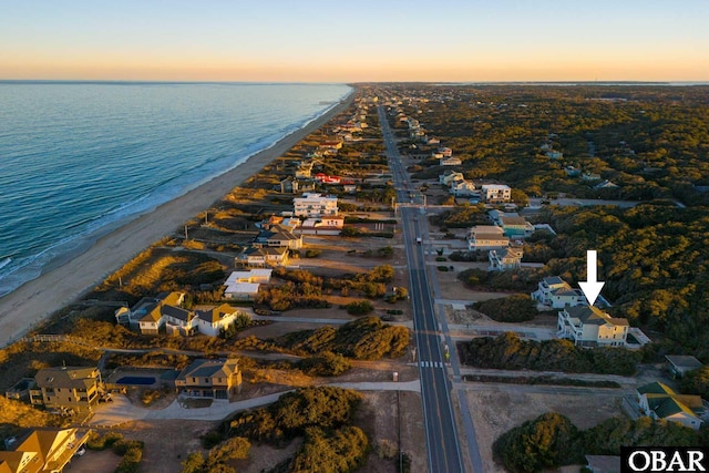 aerial view at dusk with a water view, a residential view, and a view of the beach