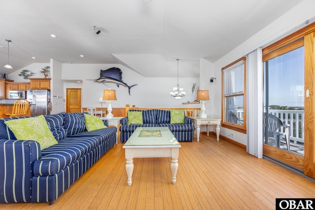 living room with lofted ceiling, light wood-type flooring, and a chandelier