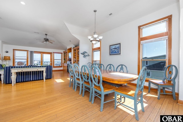 dining area featuring visible vents, baseboards, light wood-style flooring, vaulted ceiling, and ceiling fan with notable chandelier