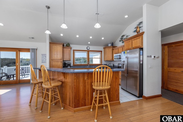 kitchen with visible vents, light wood-style flooring, appliances with stainless steel finishes, a breakfast bar area, and a center island