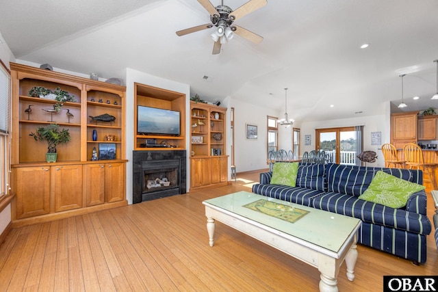 living area featuring vaulted ceiling, ceiling fan, a fireplace, and light wood-style floors