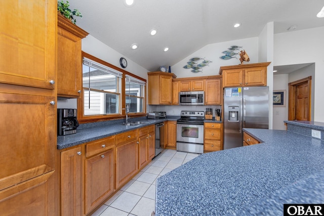 kitchen with brown cabinets, light tile patterned floors, stainless steel appliances, dark countertops, and a sink