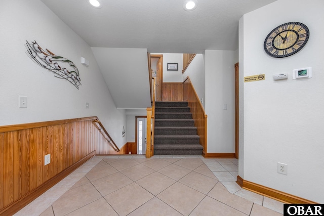 staircase with recessed lighting, wainscoting, tile patterned flooring, and wooden walls