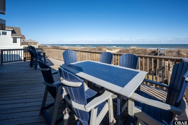 wooden terrace with a beach view, outdoor dining space, and a water view