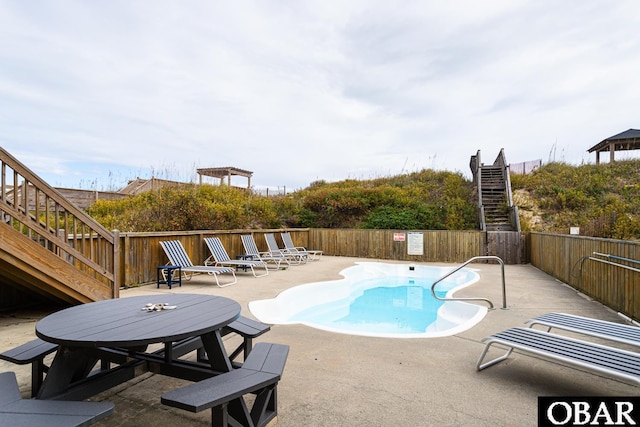 community pool featuring a patio, stairway, and fence