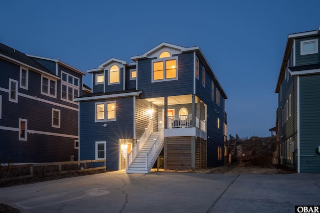 back of property with covered porch, concrete driveway, and stairway