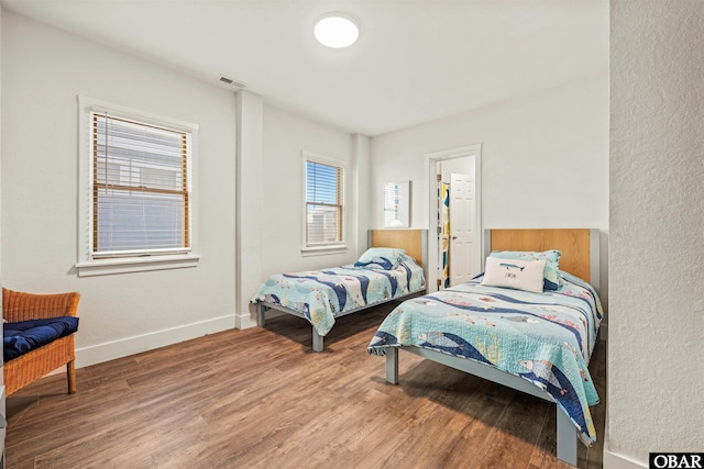 bedroom featuring wood finished floors, visible vents, and baseboards