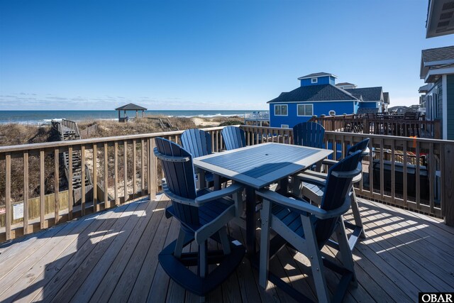 wooden deck featuring a water view and a view of the beach