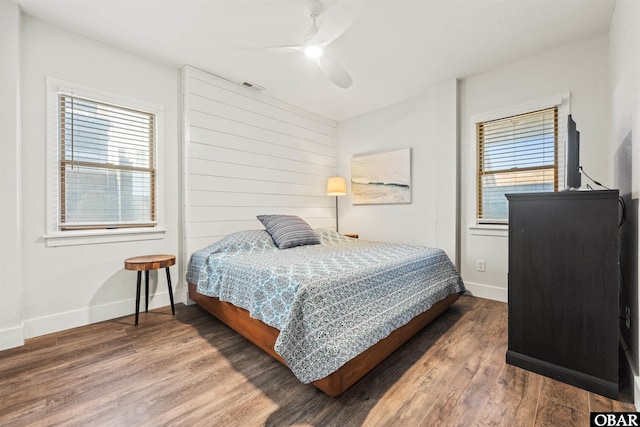 bedroom with ceiling fan, wood finished floors, visible vents, and baseboards