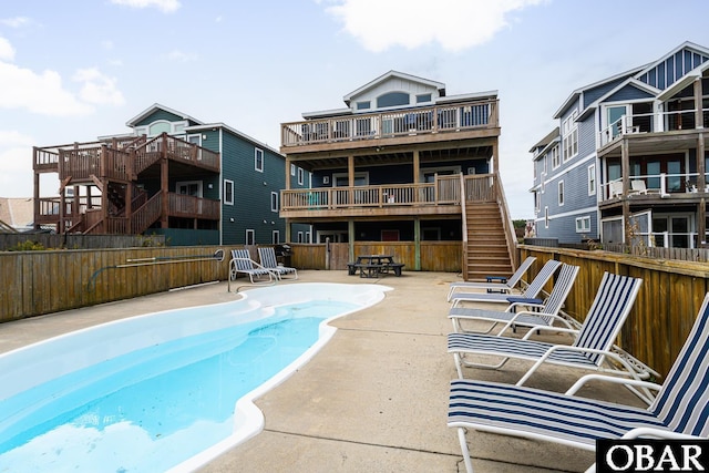 community pool with stairs, a patio area, and fence