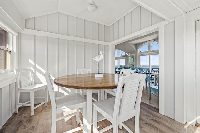 dining area featuring lofted ceiling, a water view, and wood finished floors