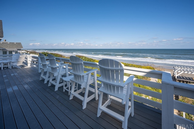 wooden terrace featuring a beach view and a water view