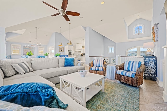 living room with high vaulted ceiling, ceiling fan with notable chandelier, and light tile patterned floors