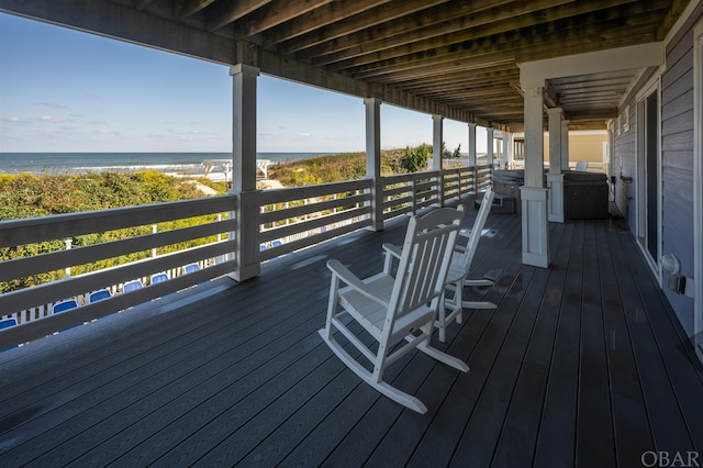 wooden deck featuring a beach view and a water view