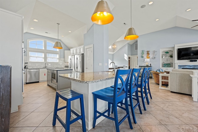 kitchen with white cabinetry, open floor plan, appliances with stainless steel finishes, a center island, and decorative light fixtures