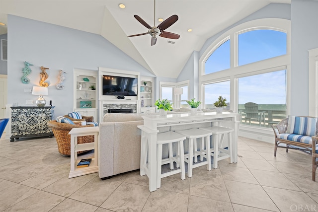 living room with light tile patterned floors, visible vents, ceiling fan, built in shelves, and a fireplace