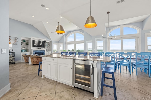 kitchen featuring pendant lighting, stone countertops, white cabinets, beverage cooler, and a kitchen breakfast bar