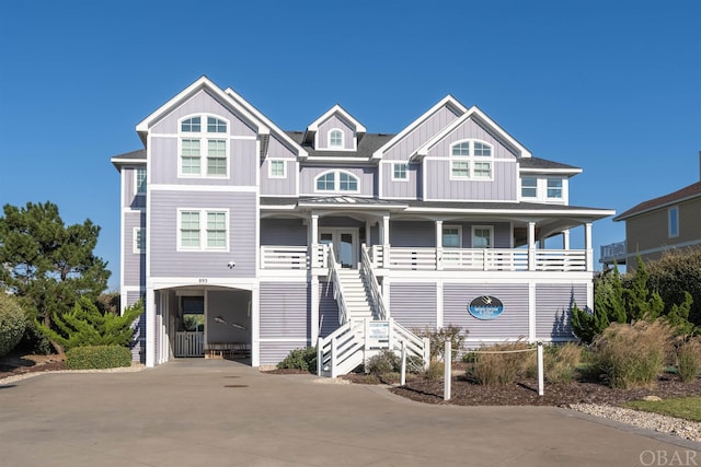 coastal home featuring covered porch, stairway, board and batten siding, a carport, and driveway