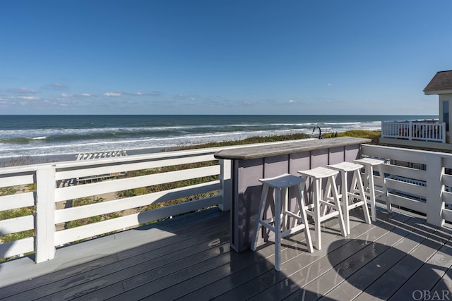 deck with a water view, outdoor dry bar, and a view of the beach