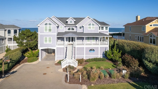 raised beach house featuring a carport, a water view, stairway, and concrete driveway