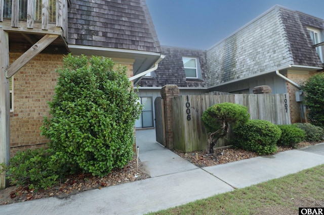 1006 Swordfish Way Unit 1006, Kitty Hawk, NC 27949 - doorway to property featuring mansard roof, fence, and brick siding