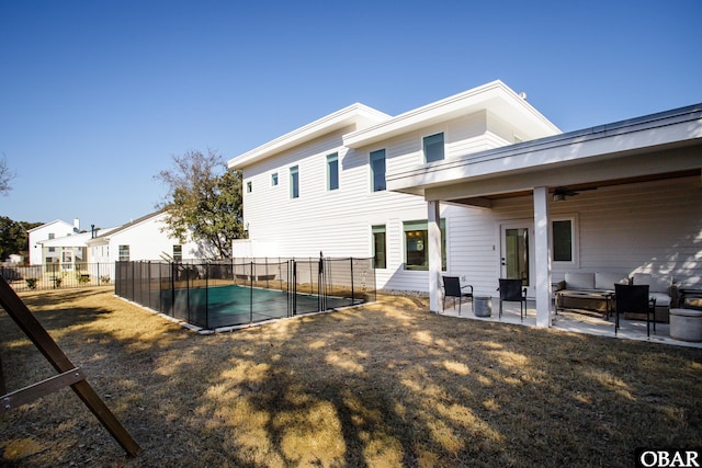 rear view of house with a lawn, fence, a fenced in pool, and a patio