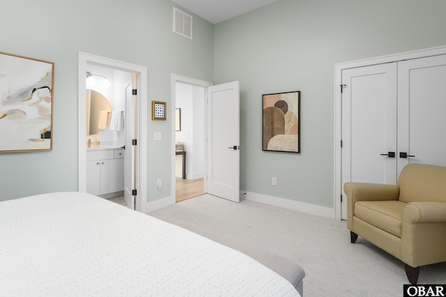 bedroom featuring a closet, visible vents, light carpet, connected bathroom, and baseboards