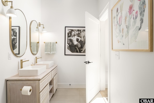 full bath featuring double vanity, tile patterned flooring, baseboards, and a sink