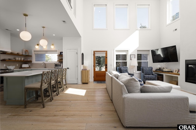 living room with plenty of natural light, light wood-style flooring, visible vents, and a glass covered fireplace