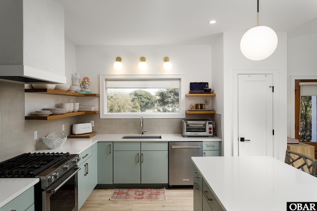 kitchen featuring a toaster, stainless steel appliances, light countertops, pendant lighting, and a sink