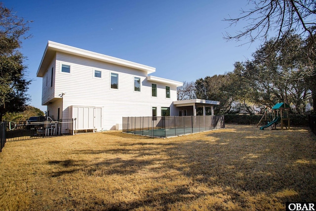 back of house with a yard, a playground, fence, and a pool