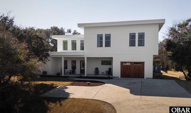 view of front of house with a garage, covered porch, driveway, and central AC unit