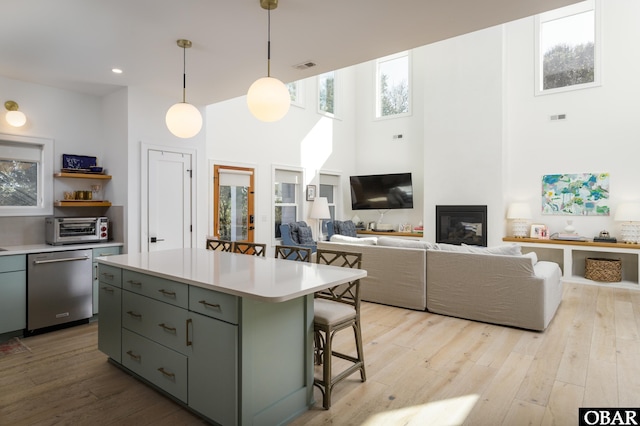 kitchen featuring light countertops, stainless steel dishwasher, a center island, a kitchen bar, and pendant lighting