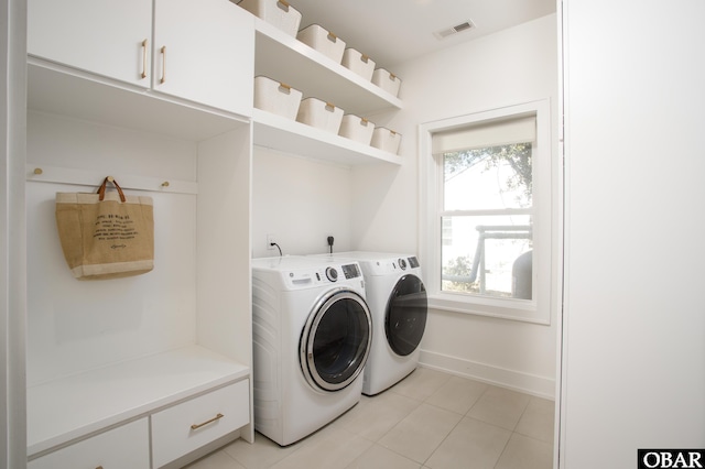 laundry area with light tile patterned floors, visible vents, cabinet space, washer and dryer, and baseboards