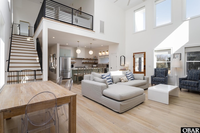 living room with stairway, visible vents, and light wood-style flooring