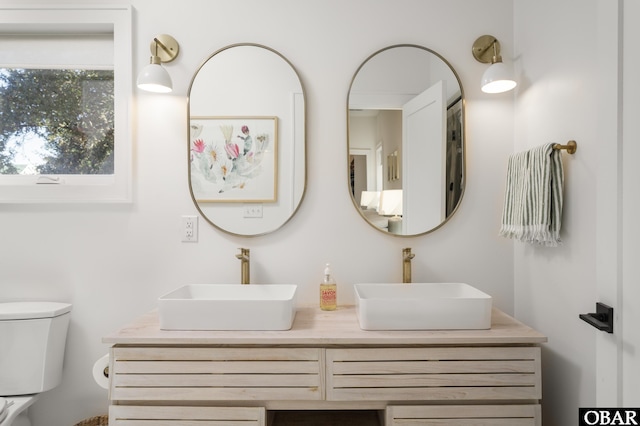 full bathroom featuring a sink, toilet, and double vanity